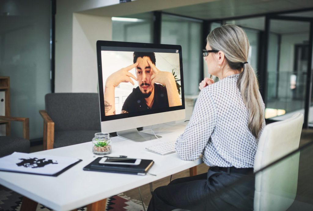 Shot of a mature psychologist conducting an online therapy session with her patient