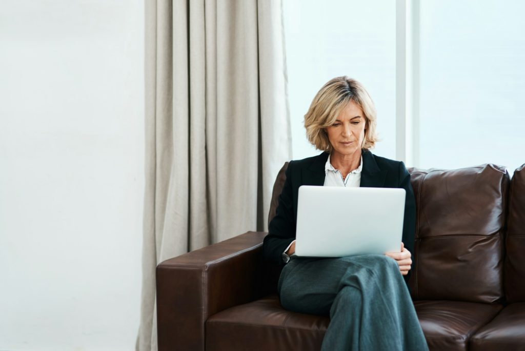 Shot of a mature psychologist sitting on a sofa and using a laptop